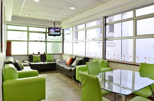 Interior de la Sala Familiar Ronald McDonald en Exequiel Gonzalez Cortes. Se ven varios sofás y una mesa con sillas alrededor. Muchas ventanas.
