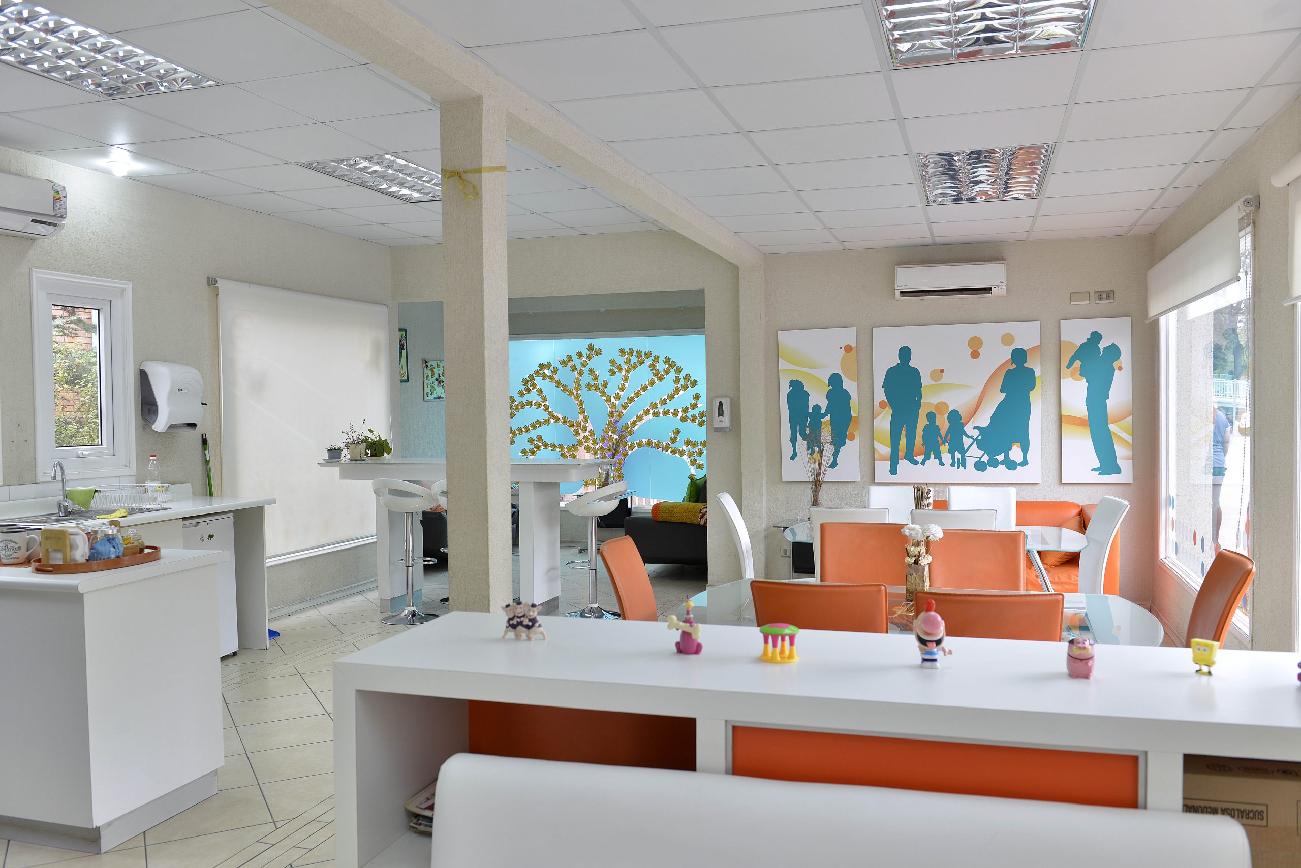 El interior de la Sala Familiar Ronald McDonald en Roberto del Rio. Se ven unas mesas, varias sillas, mesas y unos cuadros con las siluetas de familias.