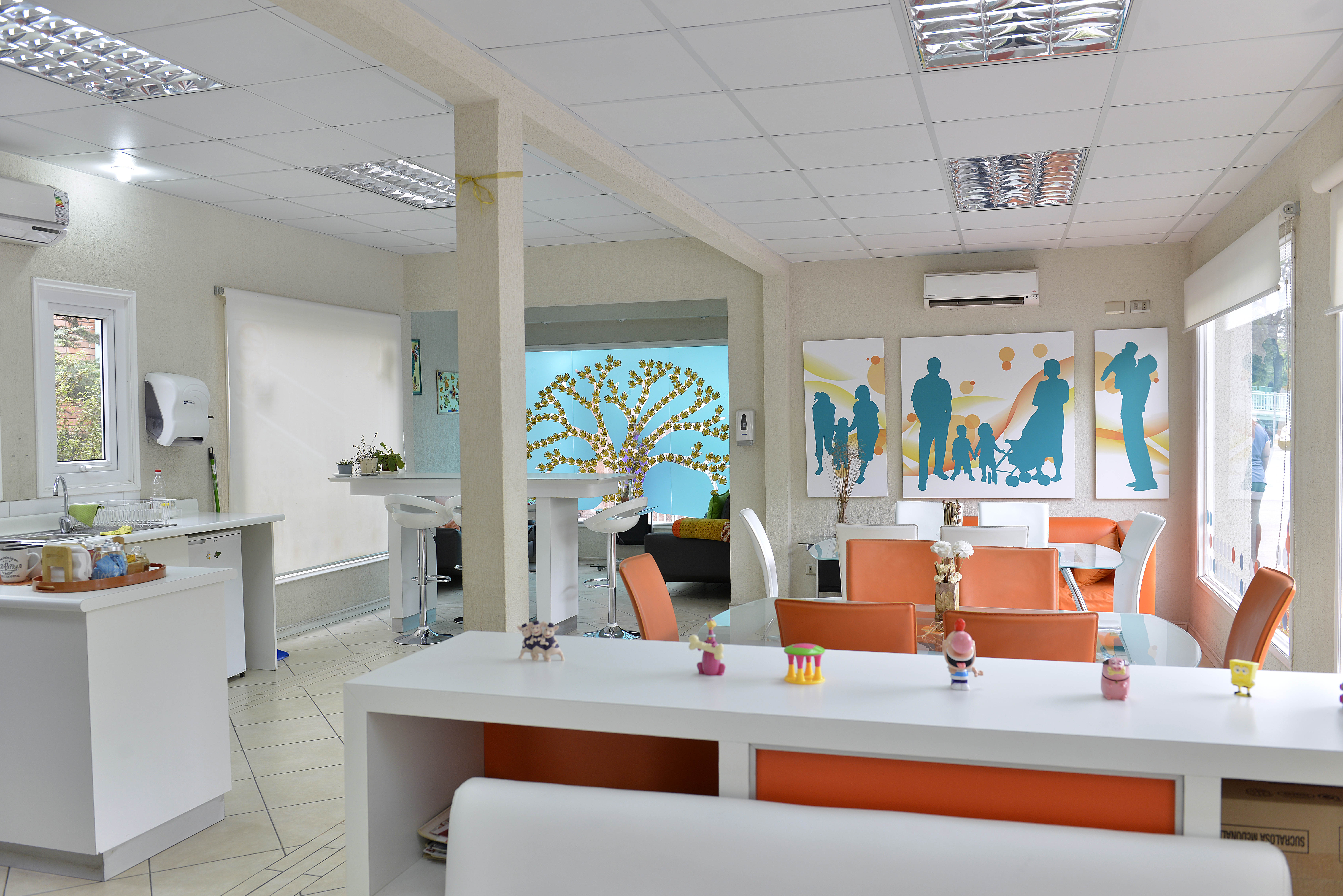 El interior de la Sala Familiar Ronald McDonald en Roberto del Rio. Se ven unas mesas, varias sillas, mesas y unos cuadros con las siluetas de familias.