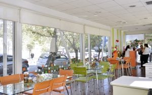 Interior de la Sala Familiar Ronald McDonald en Sotero del Rio. Se ven varias sillas naranjadas y verdes, muchas ventanas y le mesa de recepción donde hay varias mujeres hablando.